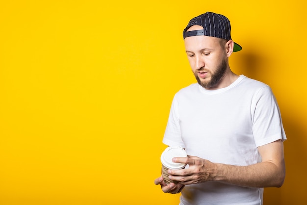 Young guy looks at a paper cup in his hands