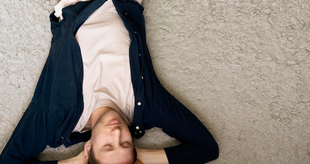 A young guy lying on the floor on the carpet at home