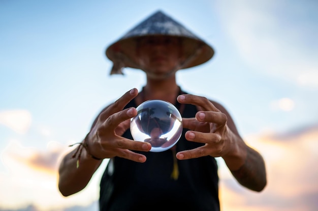 Молодой фокусник держит стеклянный шар для контактного жонглирования на закате