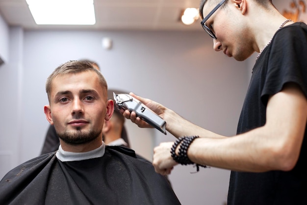 Young guy makes a short haircut in a barbershop with a trimmer closeup