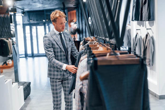 Young guy in modern store with new clothes Elegant expensive wear for men