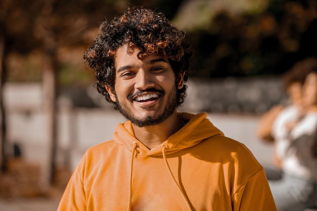 young guy in orange hoodie looking happy