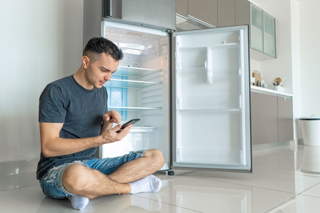 Foto il giovane ragazzo ordina il cibo utilizzando uno smartphone