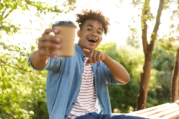 Young guy in park outdoors holding coffee