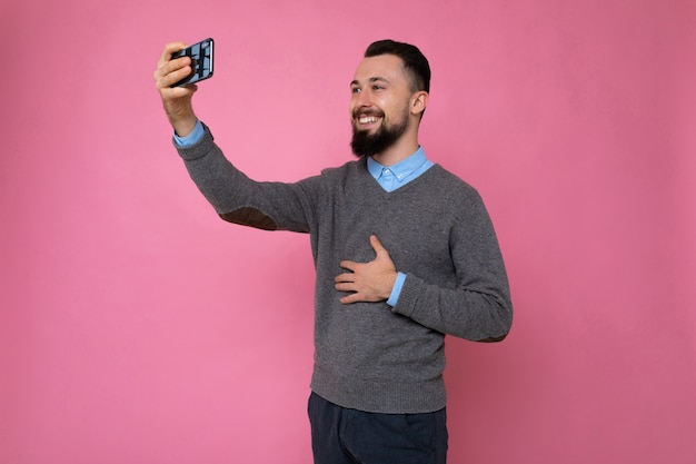 young guy on a pink background takes a selfie