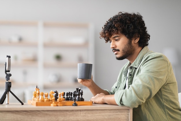 Young guy playing board game with friend at online call