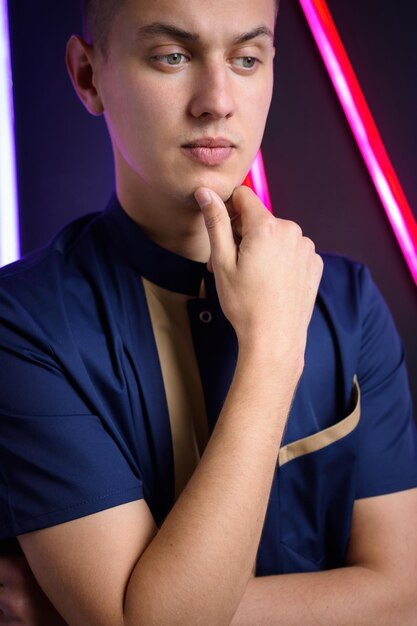 Young guy posing in the studio on a background of neon lamps