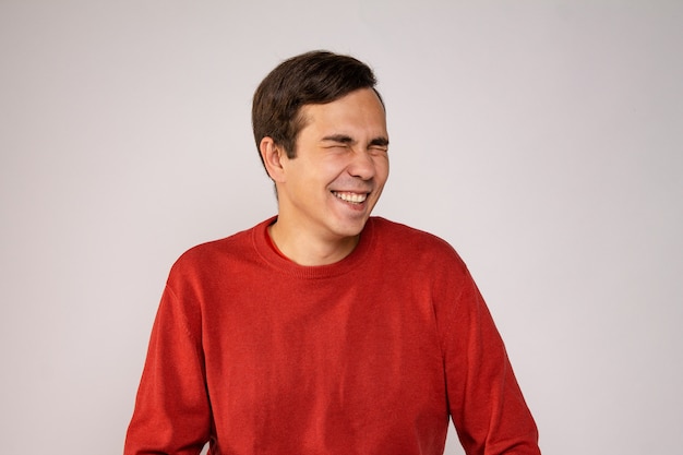 A young guy in a red sweater laughs. Portrait