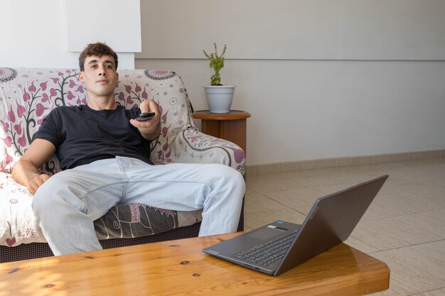 Young guy relaxing on the sofa while choosing a movie with the remote control