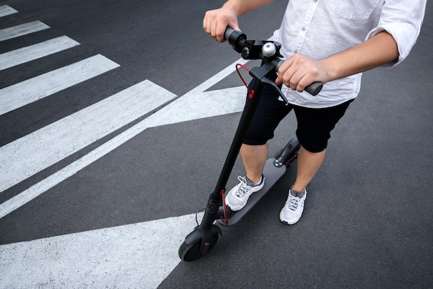 若い男は、道路標示のあるアスファルトに電動スクーターを乗せます