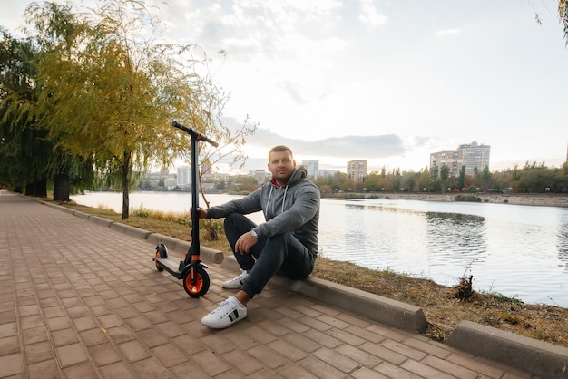 Un giovane ragazzo cavalca nel parco su uno scooter elettrico in una calda giornata autunnale