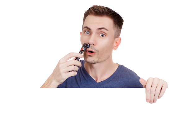 Young guy shaves his face with a razor on a white background. Handsome men are shave and beard. Copy Space.