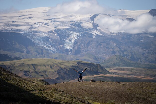 Giovane ragazzo in piedi sulle sue mani con la montagna innevata e lo sfondo del ghiacciaio sulla strada del sentiero laugavegur