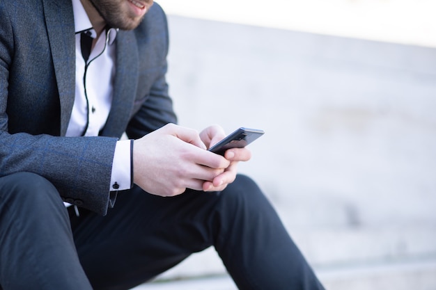 A young guy on the street sits on the phone