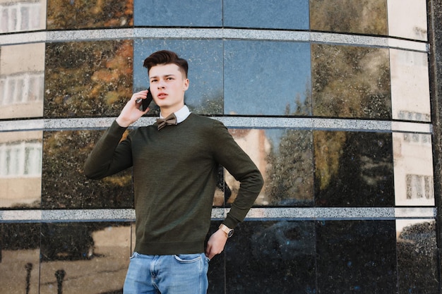 A young guy in a suit with a tie looks into a smartphone. Solves the case. Phoned. Calls on business.