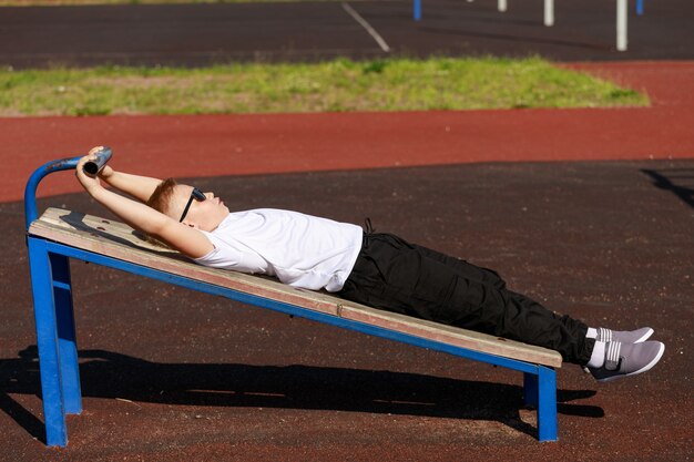 A young guy swinging the press on the sports ground in the summer. High quality photo