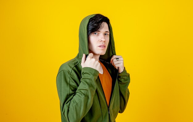 Young guy in a t-shirt and hoodie on a yellow background