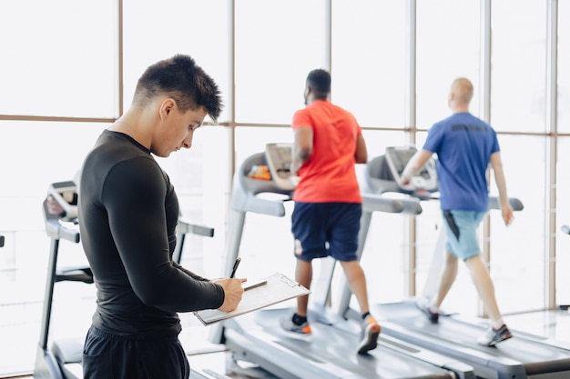 Young guy trainer takes notes in the gym. personal trainer for sports.