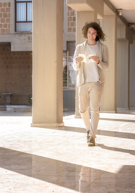 Foto il ragazzo cammina per strada leggendo un libro nel suo tempo libero