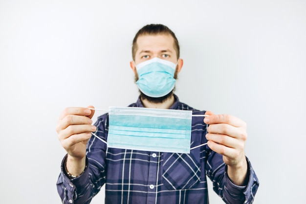 A young guy wears a medical mask to protect himself from the coronavirus. closeup portrait of a boy in a blue mask. COVID-19