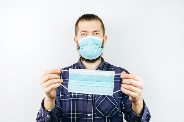 A young guy wears a medical mask to protect himself from the coronavirus. closeup portrait of a boy in a blue mask. COVID-19