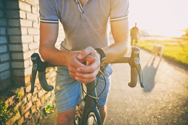 The young guy with bicycle is walking through the road