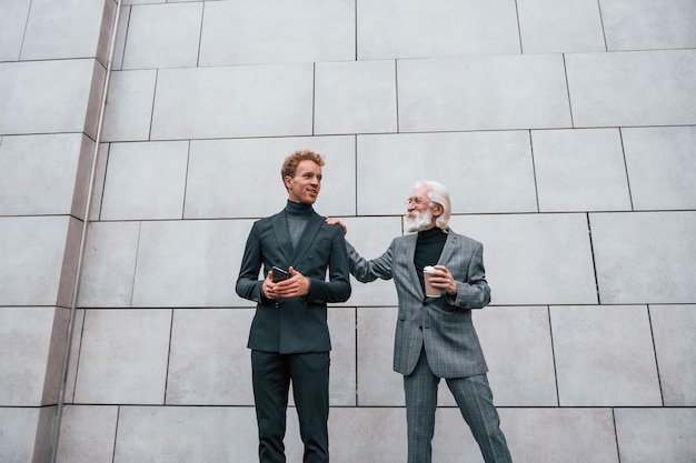エレガントな服を着た年配の男性と若い男は一緒に屋外にありますビジネスの概念