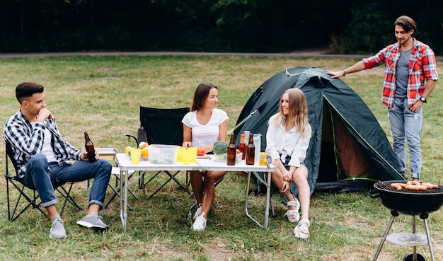 Young guys in the camping next a tent have a lunch and have a funny time