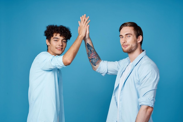 Young guys in matching tshirts and shirts fun greetings blue background friends