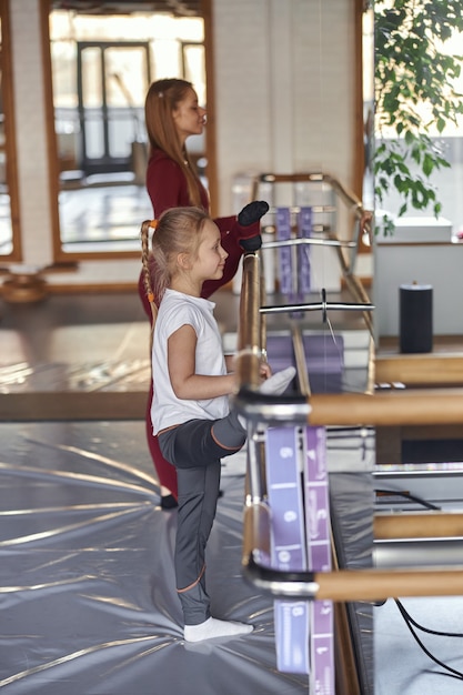 Photo young gymtastics teacher helping a girl to do exercises indoors