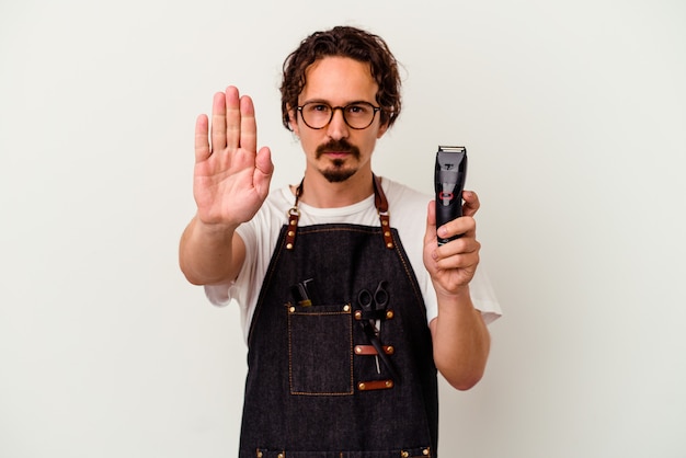 Young hairdresser caucasian man   standing with outstretched hand showing stop sign, preventing you.