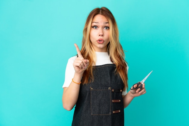 Young hairdresser girl over isolated blue background intending to realizes the solution while lifting a finger up