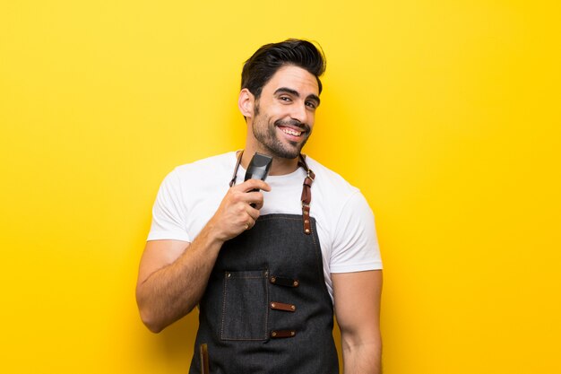 Young hairdresser man over isolated yellow wall