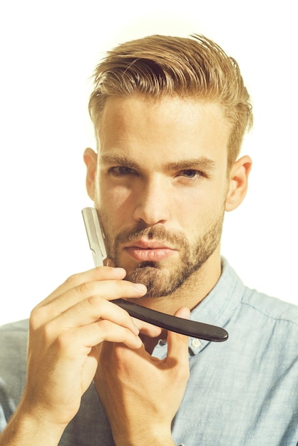 Young hairdresser wearing stylish shirt demonstrating sharp blade of his dangerous razor portrait