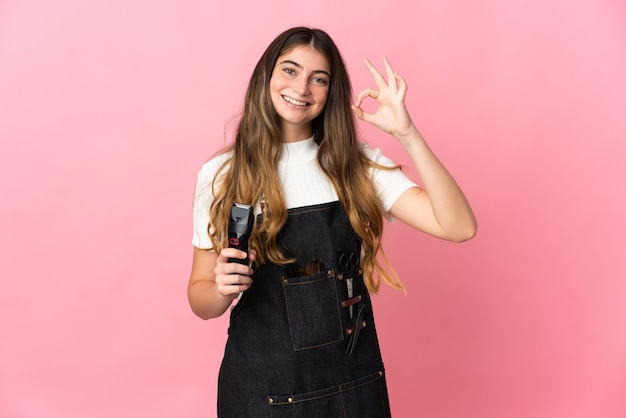 Photo young hairdresser woman isolated on pink wall showing ok sign with fingers