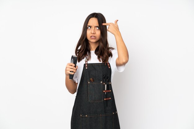 Young hairdresser woman on white wall making the gesture of madness putting finger on the head