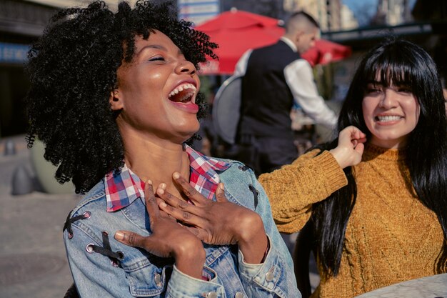 Young Haitian woman laughing out loud with her friend in an outdoor cafe