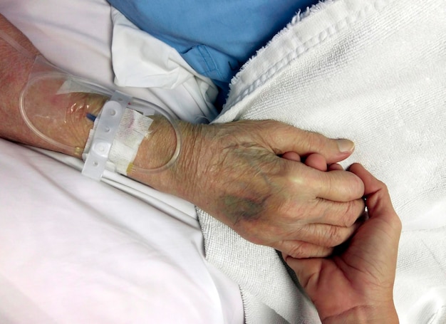 A young hand touches an old wrinkled hand