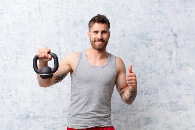 Young handosme man  against flat color wall with a dumbbell sport concept