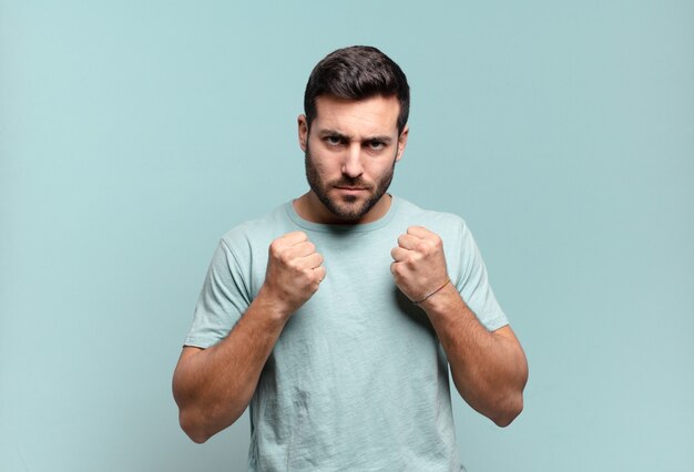 Young handsome adult man looking confident, angry, strong and aggressive, with fists ready to fight in boxing position