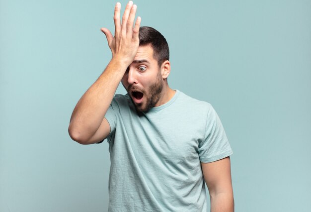 Young handsome adult man raising palm to forehead thinking oops, after making a stupid mistake or remembering, feeling dumb