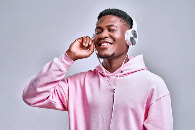 Young handsome african american man holds stylish silver earphones and smiles