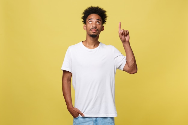 Young handsome african american man over yellow background pointing upwards.