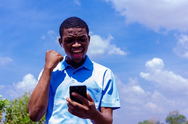 A young handsome african boy got shocked about what he saw on\
his phone