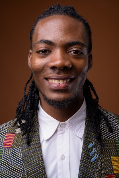 Young handsome African businessman against brown background