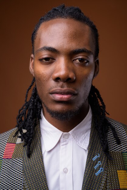 Young handsome African businessman against brown background