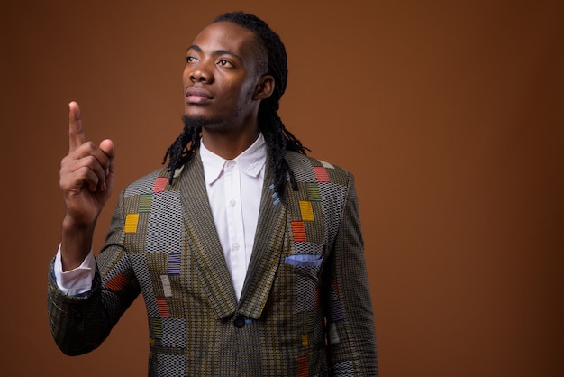 Young handsome African businessman against brown background