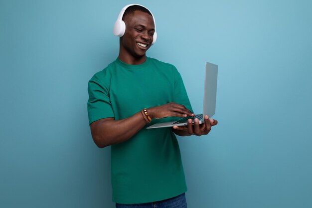 A young handsome african guy with a short haircut dressed in a basic tshirt holds a laptop for work