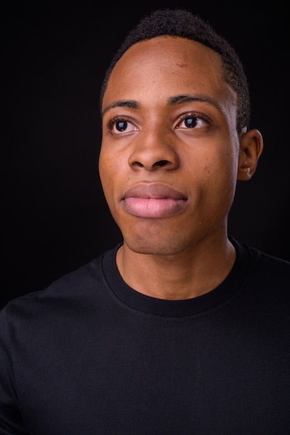 young handsome african man against black space
