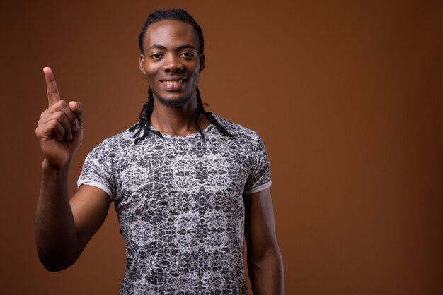 Young handsome African man against brown background